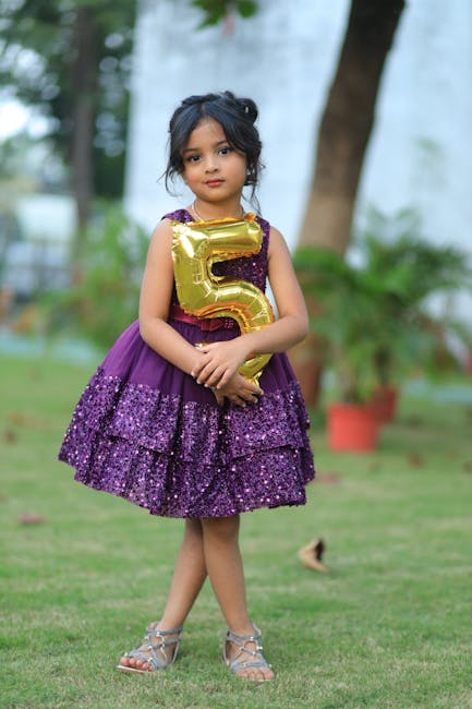 A young girl celebrating a 5th anniversary with a gold balloon